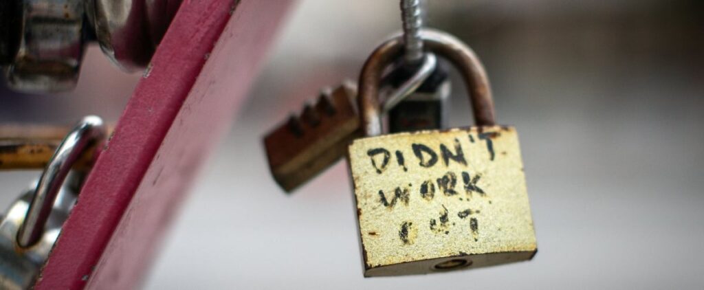 A rusty padlock with "DIDN'T WORK OUT" written in faded black marker pen.